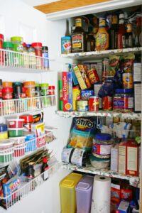 Full white pantry with wire baskets and floral shelves